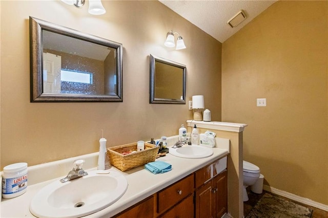 bathroom featuring a textured ceiling, vanity, lofted ceiling, and toilet