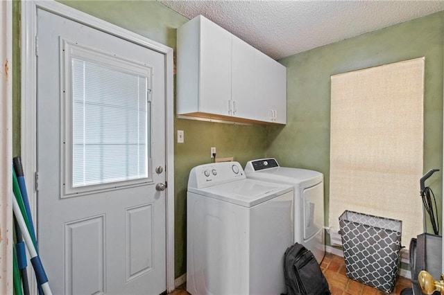 laundry area with cabinets, washer and dryer, and a textured ceiling