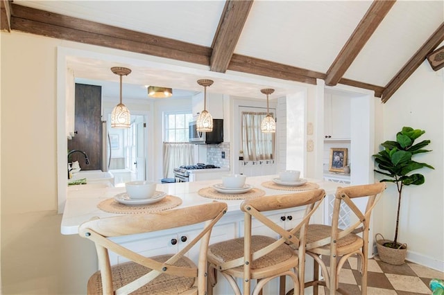 tiled dining area featuring beam ceiling and sink