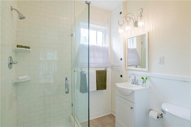 bathroom with a shower with door, vanity, tile patterned flooring, and toilet