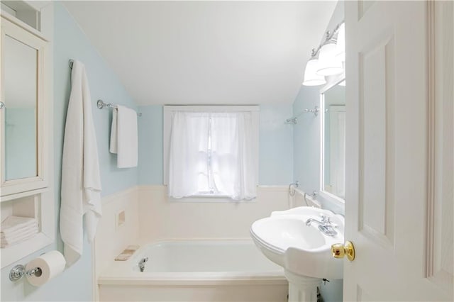 bathroom featuring a bath and vaulted ceiling