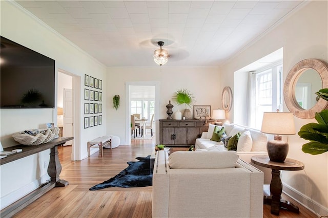 living room with ornamental molding, plenty of natural light, ceiling fan, and light wood-type flooring