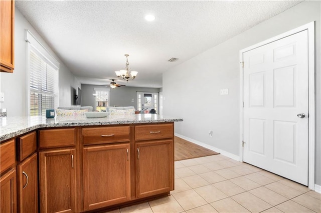 kitchen with a peninsula, visible vents, brown cabinets, and a textured ceiling