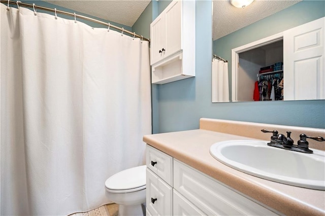 full bath featuring a textured ceiling, toilet, and vanity