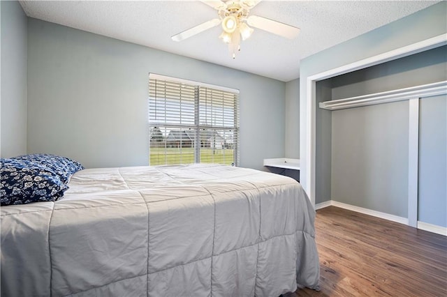 bedroom with a closet, ceiling fan, a textured ceiling, wood finished floors, and baseboards