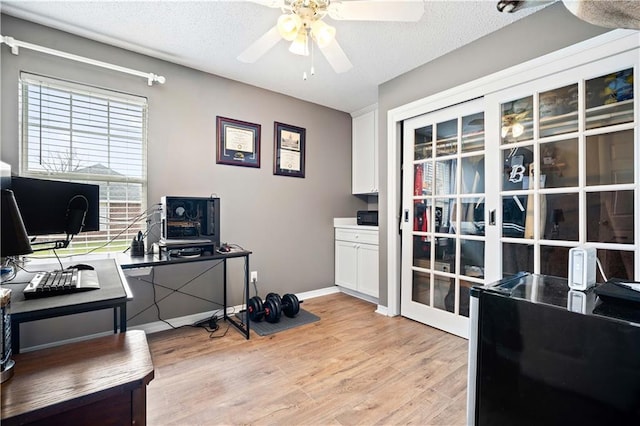 office area featuring baseboards, ceiling fan, a textured ceiling, and light wood finished floors