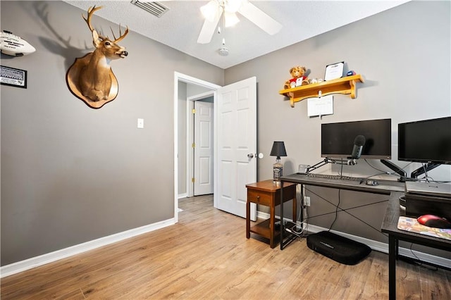 office area with light wood-type flooring, baseboards, visible vents, and ceiling fan