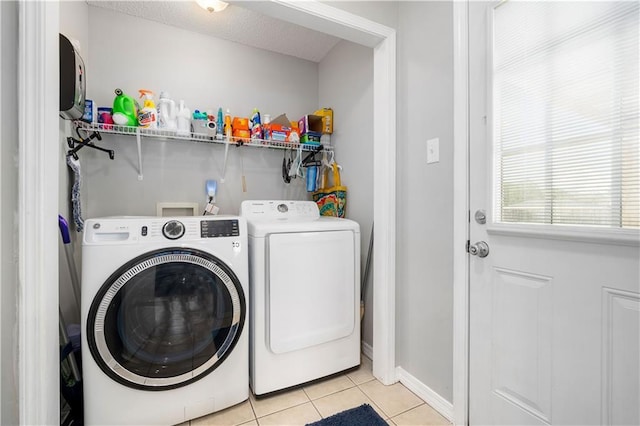 laundry room featuring light tile patterned floors, laundry area, baseboards, independent washer and dryer, and a textured ceiling