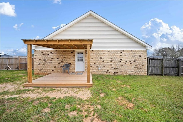 back of house featuring brick siding, a yard, a deck, and fence