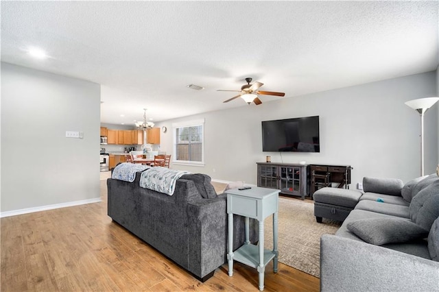 living area featuring light wood finished floors, visible vents, and baseboards