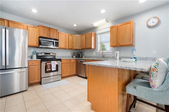 kitchen featuring a breakfast bar, stainless steel appliances, recessed lighting, a sink, and a peninsula