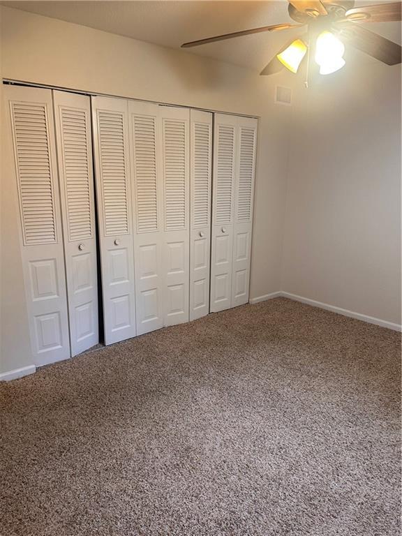 unfurnished bedroom with ceiling fan, a closet, and carpet flooring