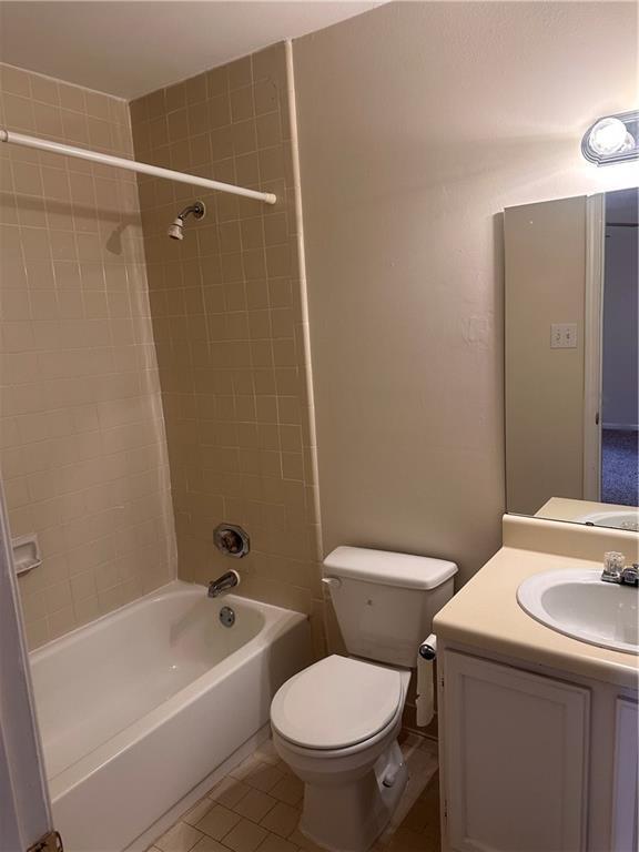 full bathroom featuring tile patterned floors, toilet, tiled shower / bath, and vanity