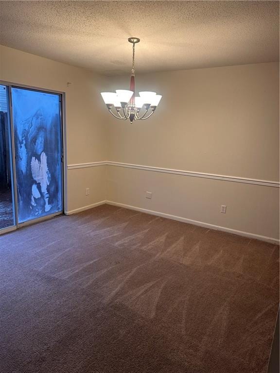 carpeted spare room with a chandelier and a textured ceiling