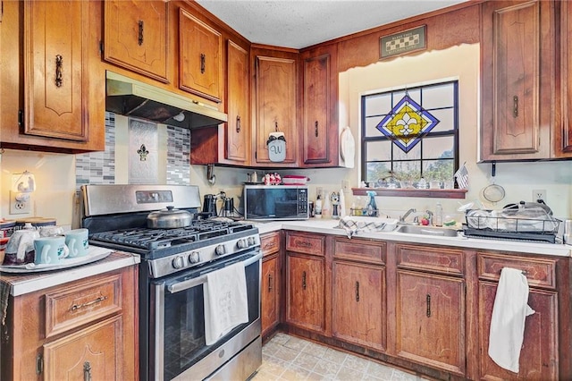 950 Red Fox Rd W, Mount Vernon, AL 36560 - kitchen featuring under cabinet range hood, light countertops, brown cabinetry, and appliances with stainless steel finishes