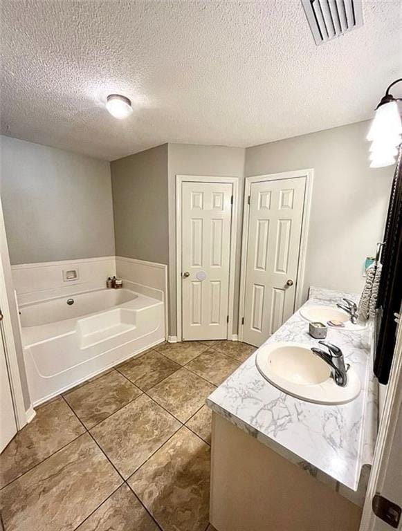 8653 Rosalene St E, Grand Bay, AL 36541 - bathroom featuring a bath, double vanity, tile patterned flooring, and a textured ceiling