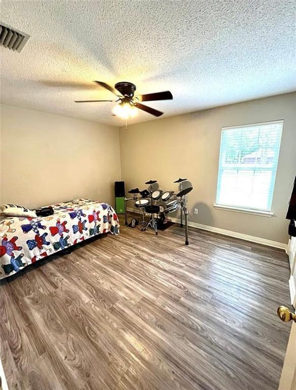 8653 Rosalene St E, Grand Bay, AL 36541 - bedroom featuring a textured ceiling, wood finished floors, a ceiling fan, and baseboards