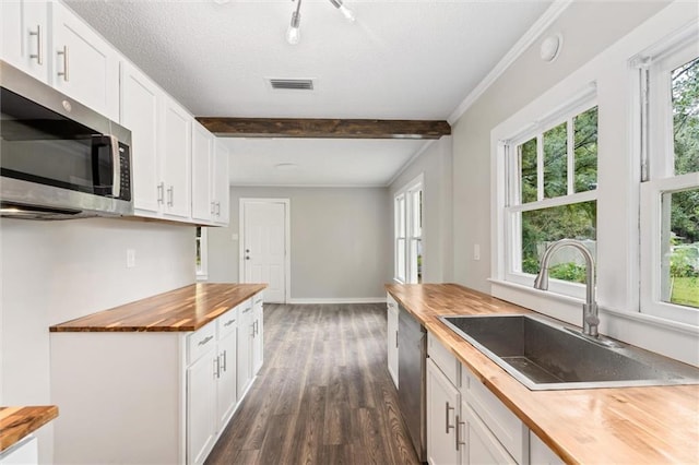 kitchen with stainless steel appliances, sink, butcher block countertops, and white cabinets