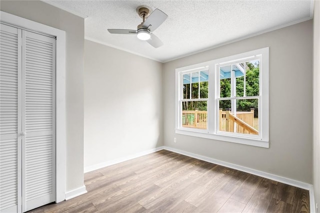 interior space with a textured ceiling, light hardwood / wood-style flooring, ornamental molding, a closet, and ceiling fan