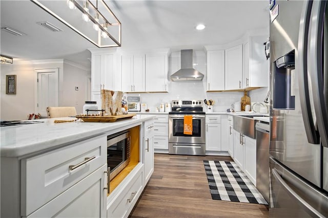 kitchen with wall chimney range hood, light stone countertops, appliances with stainless steel finishes, white cabinetry, and dark wood-type flooring