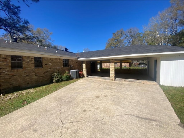 exterior space featuring cooling unit, brick siding, driveway, and a carport