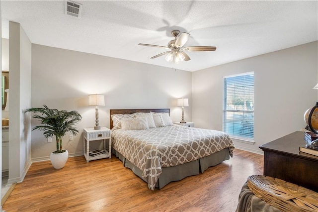 bedroom featuring ceiling fan, hardwood / wood-style floors, and a textured ceiling