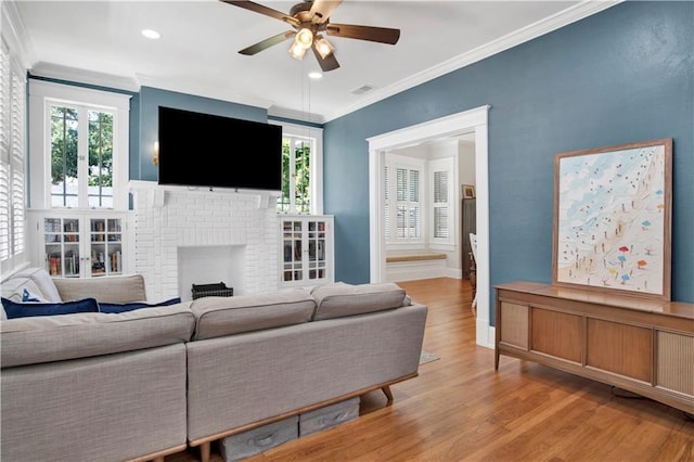 303 Monterey St S, Mobile, AL 36604 - living room featuring ceiling fan, crown molding, light wood-type flooring, healthy amount of natural light, and a brick fireplace