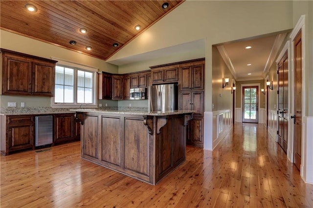 kitchen with light stone counters, light hardwood / wood-style flooring, stainless steel appliances, a center island, and a wealth of natural light