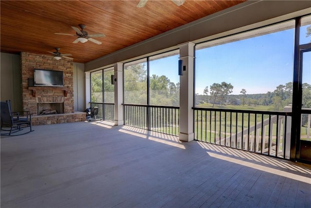 unfurnished sunroom with an outdoor stone fireplace, ceiling fan, and wooden ceiling