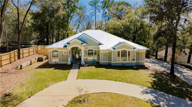 view of front of home with a front lawn, fence, and metal roof