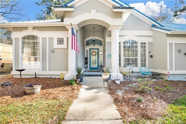 entrance to property with stucco siding, a porch, and metal roof