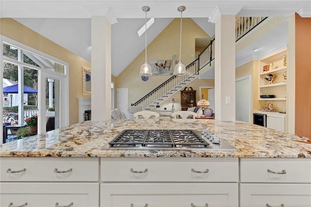 kitchen featuring stainless steel gas cooktop, white cabinetry, hanging light fixtures, built in features, and light stone countertops