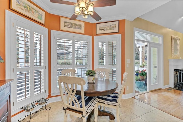 tiled dining area with ornamental molding and ceiling fan