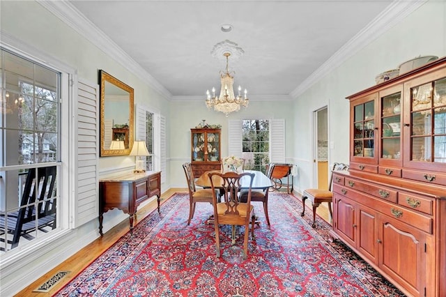 dining area with an inviting chandelier, crown molding, and light hardwood / wood-style floors