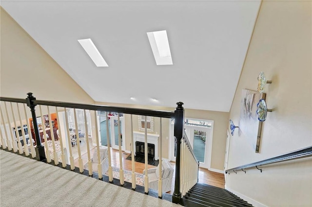 stairway featuring vaulted ceiling with skylight and hardwood / wood-style floors