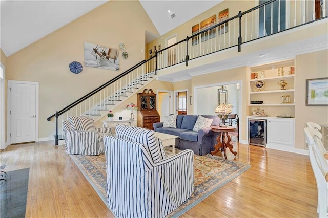 living room featuring built in features, bar, high vaulted ceiling, beverage cooler, and light wood-type flooring