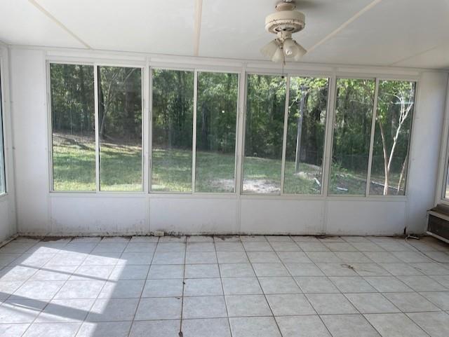 unfurnished sunroom featuring tile patterned flooring, a wealth of natural light, and ceiling fan