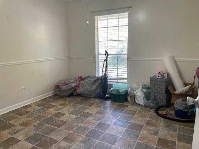 unfurnished room with stone finish floor and baseboards