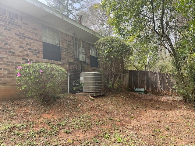 view of yard with central AC and fence