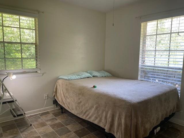 bedroom with baseboards and multiple windows