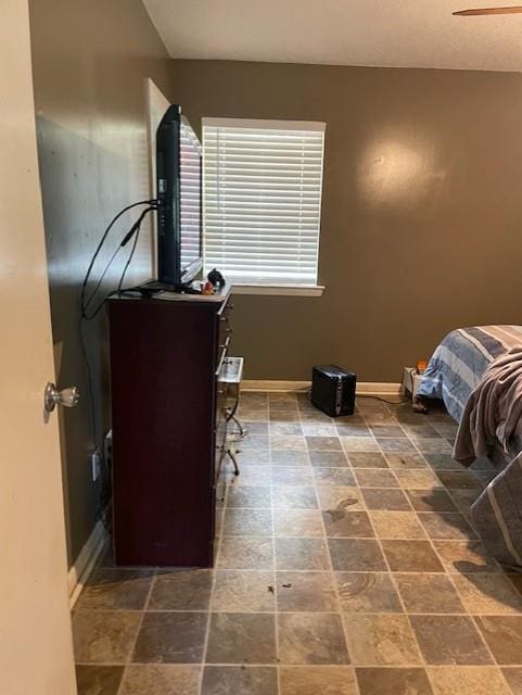 bedroom with baseboards and stone finish flooring