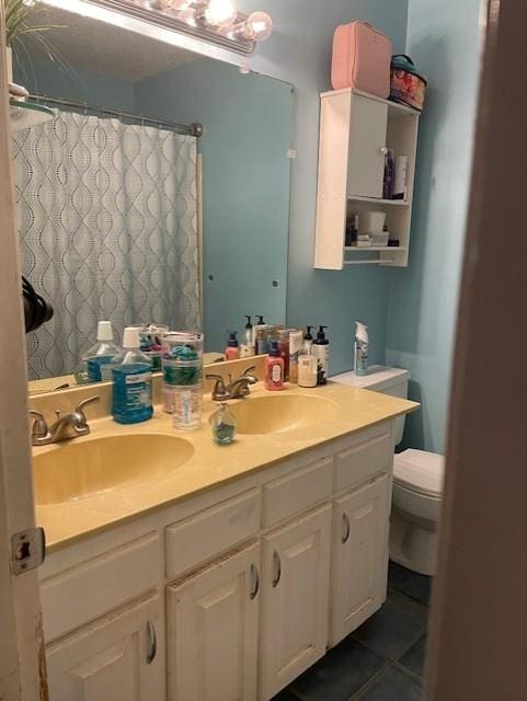 bathroom with double vanity, toilet, tile patterned flooring, and a sink