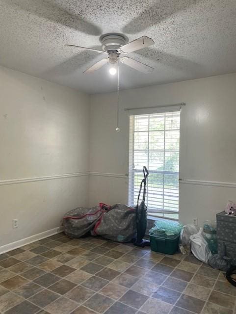 unfurnished room featuring a textured ceiling, baseboards, and ceiling fan