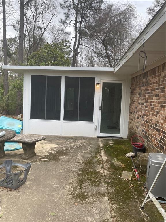 view of exterior entry featuring a patio area and brick siding