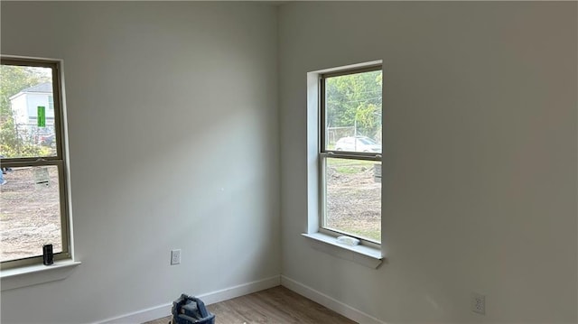 unfurnished room featuring a wealth of natural light, baseboards, and wood finished floors