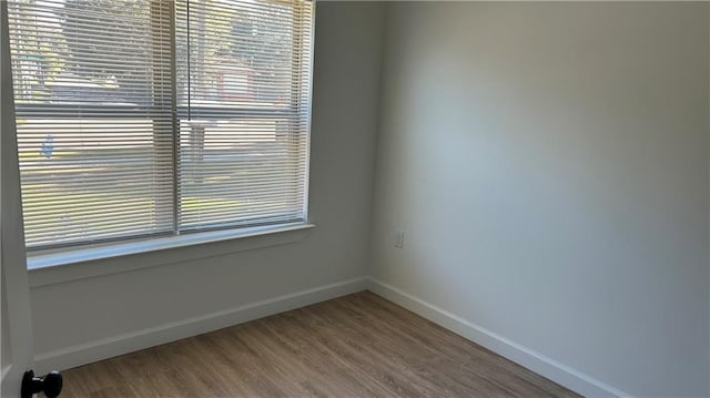 spare room featuring baseboards and wood finished floors