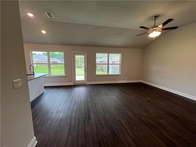 unfurnished living room featuring dark wood-style flooring, visible vents, a ceiling fan, vaulted ceiling, and baseboards