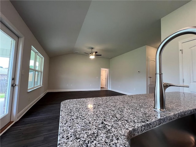 interior space with lofted ceiling, sink, dark hardwood / wood-style floors, ceiling fan, and light stone countertops