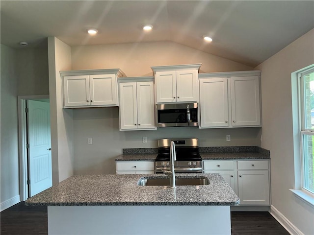 kitchen featuring lofted ceiling, stainless steel appliances, a center island with sink, and white cabinets