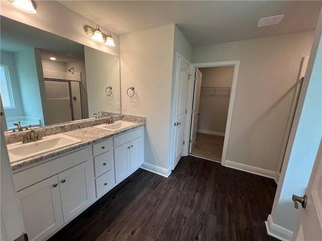 full bath with wood finished floors, a stall shower, a sink, and baseboards